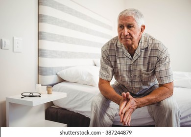 Senior Man Sitting On Bed In Bedroom