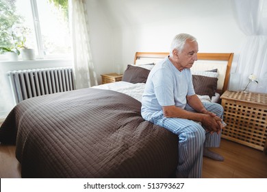 Senior Man Sitting On Bed In Bedroom