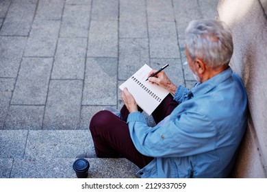 A Senior Man Sitting Outside And Writing To Do List.