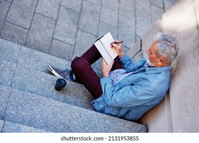 A Senior Man Sitting Outside And Writing To Do List.