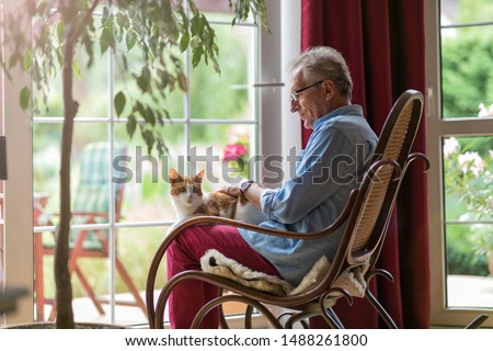 Senior man sitting in a rocking chair with his cat in his lap
