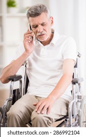 Senior Man Sitting In Wheelchair At Home And Talking On Phone.