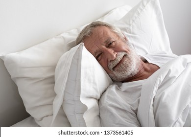 senior man sleep with smile on bed in room