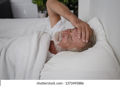 senior man sleeping alone and headache or dreaming nightmare on bed in room - Powered by Shutterstock