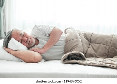 Senior man sleeping in bed. Old asian man sleeping comfortably in bed with curtain open. Senior lifesyle concept.