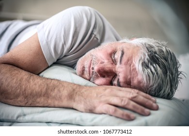 Senior Man Sleeping In Bed. Space For Copy.