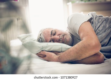 Senior Man Sleeping In Bed. Space For Copy.