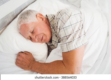 Senior man sleeping on bed in bedroom