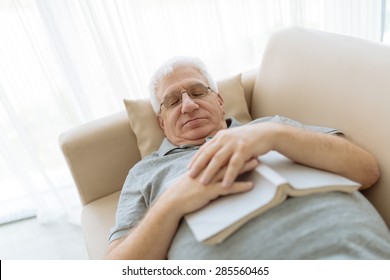 Senior man sleeping on sofa with a book - Powered by Shutterstock