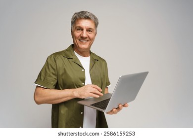 Senior man smiles while using laptop in a minimalistic indoor space during the day