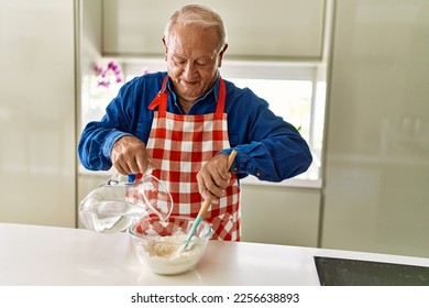 Senior man smiling confident cooking dough at kitchen - Powered by Shutterstock