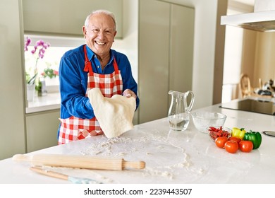 Senior man smiling confident holding dough with hands at kitchen - Powered by Shutterstock