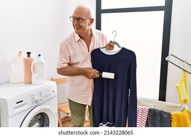 Senior Man Smiling Confident Using Clean Pet Hair Roller At Laundry Room