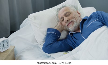 Senior man smiling while asleep in the morning, pleased pensioner lying in bed - Powered by Shutterstock