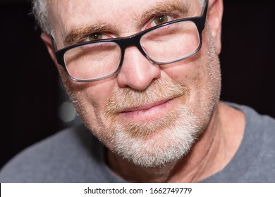 Senior Man With Smirk Looks Straight Ahead Wearing Glasses