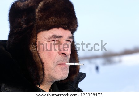 Senior man is smoking sigarete outdoor in winter