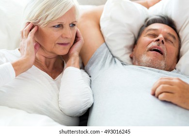 Senior Man Snoring And Woman Covering Ears
