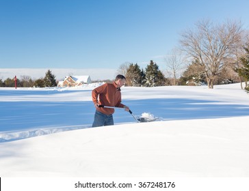 Senior Man With Snow Shovel Looking At Snow Drifts On Driveway As He Tries To Dig Out From The Blizzard