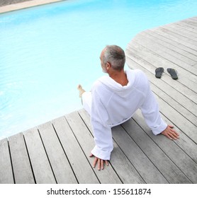 Senior Man With Spa Bathrobe Relaxing By Pool