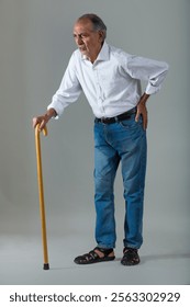 Senior man standing in back pain holding a walking stick (Health and fitness)