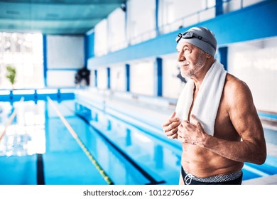 Senior man standing by the indoor swimming pool.