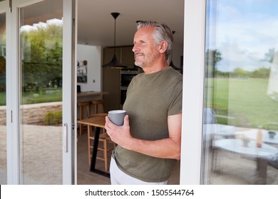 Senior Man Standing And Looking Out Of Kitchen Door Drinking Coffee - Powered by Shutterstock