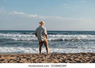 A senior man standing thoughtfully on the beach, gazing at the v - Powered by Shutterstock