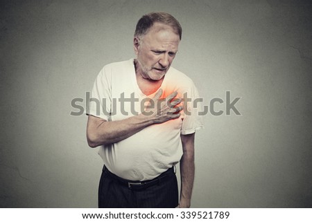 senior man suffering from bad pain in his chest heart attack isolated on gray background