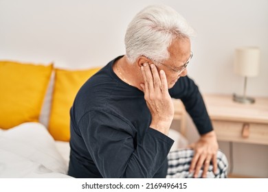 Senior Man Suffering For Ear Ache Sitting On Bed At Bedroom