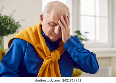 Senior man suffering from a headache. Old, retired, white haired man having a migraine and holding his hand on his head. Pain, headache, disease, health problem concept - Powered by Shutterstock