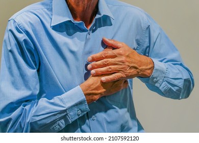 Senior man suffering from heart attack. Closeup shot of a mature man holding his chest in discomfort