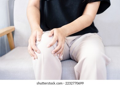 senior man suffering from knee pain sitting on sofa  - Shutterstock ID 2232770699
