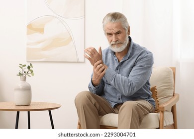 Senior man suffering from pain in his wrist at home. Arthritis symptoms - Shutterstock ID 2293004701
