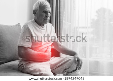 Senior man is suffering from problems with a digestion at home