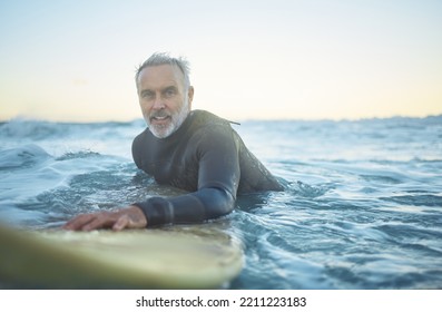 Senior Man, Surfing In The Ocean Of Indonesia And Free To Travel The World In Retirement Life. Retired Surfer, Swimming In The Sea For Fitness And Exercise Looking To Catch A Perfect Wave On Holiday