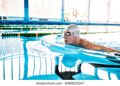 Senior man swimming in an indoor swimming pool. - Powered by Shutterstock