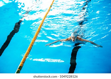 Senior man swimming in an indoor swimming pool. - Powered by Shutterstock