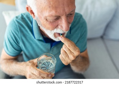 Senior Man Takes Pill With Glass Of Water In Hand. Stressed Mature Man Drinking Sedated Antidepressant Meds. Man Feels Depressed, Taking Drugs. Medicines At Work