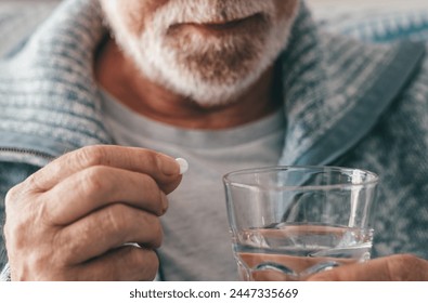 Senior man takes pill with glass of water in hand. Stressed elderly bearded man drinking sedated antidepressant meds. Man feels depressed, taking drugs. Medicines at work - Powered by Shutterstock