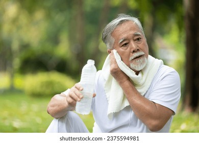 senior man taking a break from workout and wiping sweat on face with a towel - Powered by Shutterstock