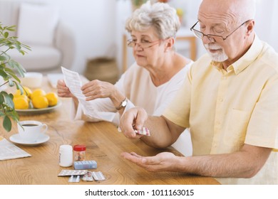 Senior man taking medication for diabetes while his wife reading a prescription