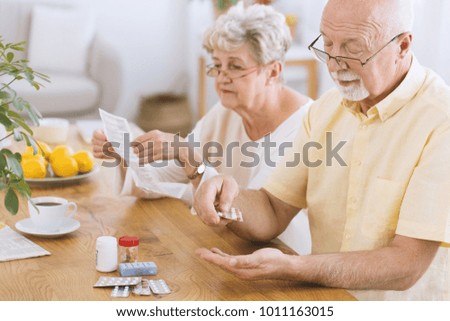 Senior man taking medication for diabetes while his wife reading a prescription