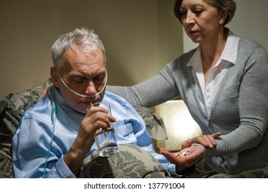 Senior Man Taking Medication With Water Caring Wife Helping