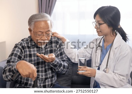 Senior man taking medication while doctor provides assistance and water during home healthcare visit. Elderly care, prescription support, medical treatment, caregiver help concept.
