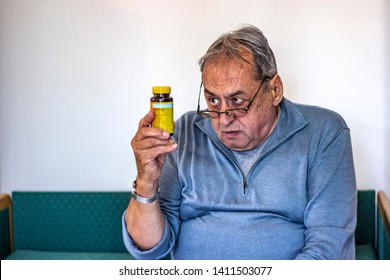 Senior Man Taking Medicine At Home. Older Man Taking Daily Medicine To Consume. Man Pouring A Pill From Into Hand. 