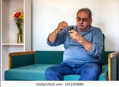 Senior Man Taking Medicine At Home. Older Man Taking Daily Medicine To Consume. Man Pouring A Pill From Into Hand. 