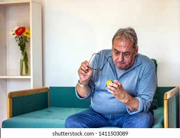 Senior Man Taking Medicine At Home. Older Man Taking Daily Medicine To Consume. Man Pouring A Pill From Into Hand. 