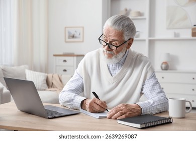 Senior man taking notes while learning online at desk indoors. Self-study - Powered by Shutterstock - Get 15% off with code: PIKWIZARD15