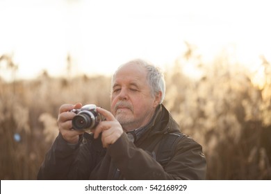 Senior man taking a picture in huge forest by digital camera during lovely sunset (color toned image) - Powered by Shutterstock