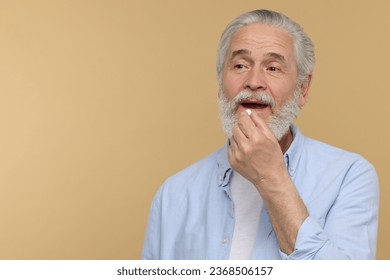 Senior man taking pill on beige background. Space for text - Powered by Shutterstock